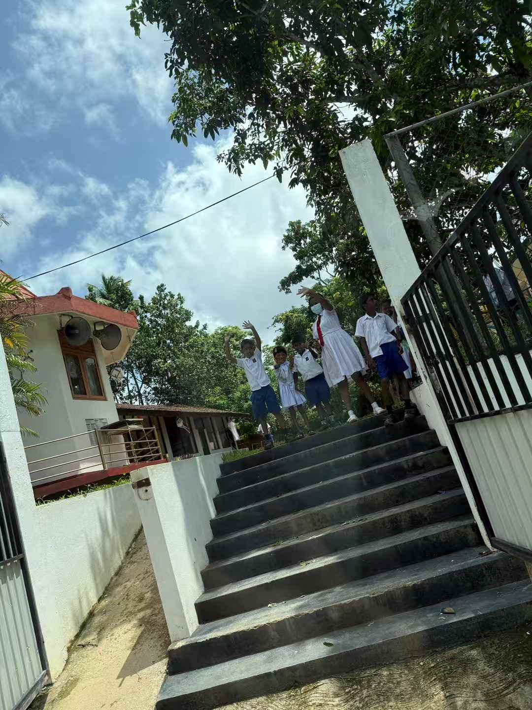 Students waving from steps during a Sri Lanka service day
